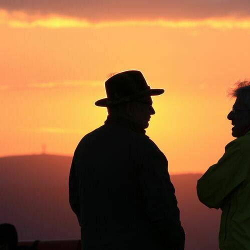 Unterhaltung zwischen zwei M�nnern, w�hrend im Hintergrund die Sonne aufgeht.