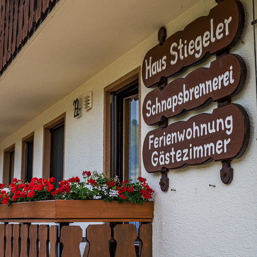 Holzschilder an der Hausfassade mit der Beschriftung Haus Stiegeler, Schnapsbrennerei und Ferienwohnung, G&auml;stezimmer  - 